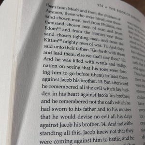 K&ouml;nnte beinhalten: Offenes Buch mit Text aus "The Book of Jubilees" auf einer cremefarbenen Seite. Der Text ist schwarz, mit der Seitenzahl 574 sichtbar. Der Buchrand ist auf der linken Seite sichtbar.