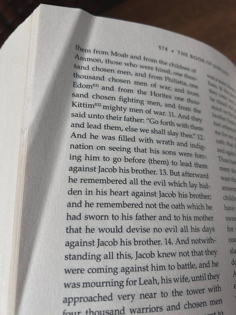K&ouml;nnte beinhalten: Offenes Buch mit Text aus "The Book of Jubilees" auf einer cremefarbenen Seite. Der Text ist schwarz, mit der Seitenzahl 574 sichtbar. Der Buchrand ist auf der linken Seite sichtbar.