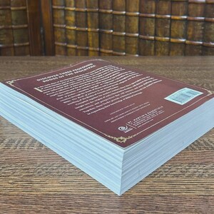 K&ouml;nnte beinhalten: Ein Hardcover-Buch mit einem weinroten Einband und wei&szlig;en Seiten. Der Einband tr&auml;gt den wei&szlig;en Text "Discover These Profound Books of the Apocrypha". Das Buch liegt auf einer Holzoberfl&auml;che.
