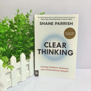 May include: A white book titled Clear Thinking by Shane Parrish with a blue dotted spiral graphic on the cover. The text reads An indispensable guide to making smarter decisions each day, New York Times Bestseller, and Turning Ordinary Moments into Extraordinary Results.
