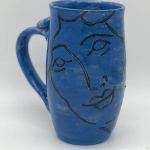 May include: A set of three ceramic mugs with a speckled, matte finish. The mugs are in shades of cream, light gray, and dark gray. Each mug has a simple, minimalist design and a rounded handle.