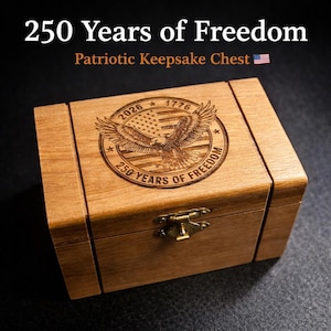 May include: A wooden keepsake chest with the text "250 Years of Freedom" and "Patriotic Keepsake Chest." The chest features an engraved design of an eagle, American flag, and the years 1776 and 2026. It has a brass clasp.
