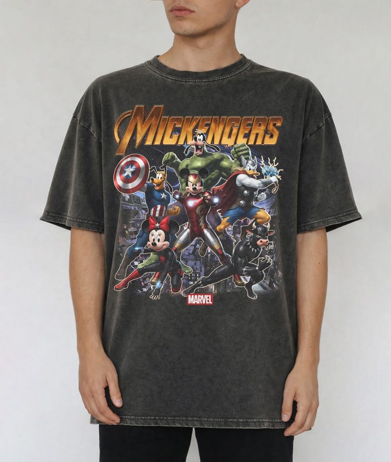 May include: A charcoal grey acid-wash t-shirt featuring a graphic print titled MICKENGERS with Disney characters dressed as Marvel superheroes, including Mickey Mouse as Iron Man, Minnie Mouse as Black Widow, and Goofy as the Hulk.
