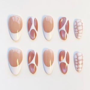 May include: A set of ten artificial nails in various designs. Some nails feature a nude base with a white tip, while others have a white and brown abstract pattern. One nail has a textured, light brown pattern.