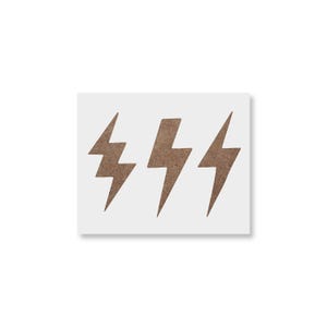 May include: Three brown lightning bolt shapes are arranged horizontally on a white background. The lightning bolts have a textured appearance, suggesting a wood or cork material. The image is a simple, graphic design.