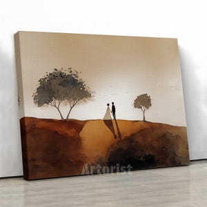 May include: Watercolor painting of a couple standing on a hill, holding hands. The artwork features a warm color palette of browns and tans, with two trees and a soft, diffused light in the background. The canvas is mounted on a wooden frame.