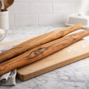 May include: Two cylindrical wooden rolling pins with a distinct natural grain pattern and visible knots. The rolling pins are crafted from a warm-toned brown wood, featuring a smooth, polished surface and rounded ends, showcasing the organic texture.