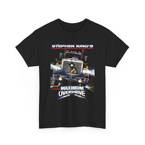 Puede incluir: Una camiseta negra de manga corta con un estampado gráfico de un camión con una figura verde brillante en la parrilla. El texto dice STEPHEN KING'S MASTERPIECE OF HORROR DIRECTED BY THE MASTER HIMSELF y MAXIMUM OVERDRIVE en color blanco.