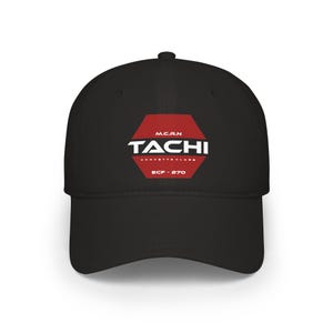 May include: A black baseball cap featuring a red hexagonal emblem on the front. The emblem contains the white text M.C.R.N, TACHI, CORVETTE CLASS, and ECF-270. The cap has a structured crown, a curved brim, and a button at the top centre.
