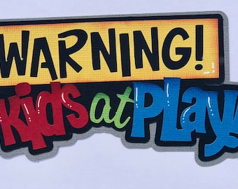 May include: A colorful sign with the words "WARNING! Kids at Play" in bold, playful lettering. The sign has a yellow background with black text and a red, green, and blue text design, perfect for a child's room or play area.