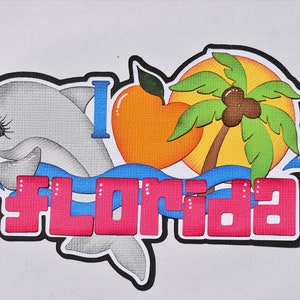 May include: A colorful illustration of a dolphin, a palm tree, a heart-shaped orange, and the words "I Love Florida" in pink letters. The image is set against a white background.