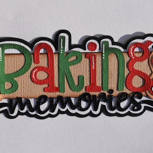 May include: A red and green "Baking Memories" sign with a rolling pin design. The sign is decorated with white polka dots and stars.