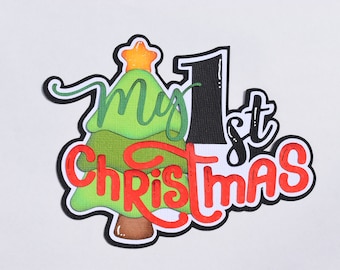 Puede incluir: Un árbol de Navidad verde con una estrella en la parte superior y las palabras "My 1st Christmas" en letras rojas y negras.