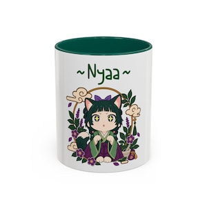 Puede incluir: Una taza de cerámica blanca con interior y borde verde oscuro. El exterior presenta un personaje de dibujos animados con orejas de gato, pelo oscuro y un traje verde y morado. El texto ~Nyaa~ está impreso sobre el personaje y flores.