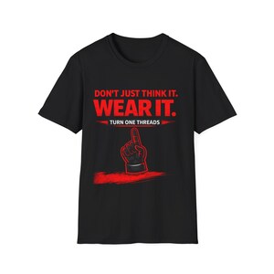 May include: Black t-shirt with red text that reads "DON'T JUST THINK IT. WEAR IT." and "TURN ONE THREADS." A red graphic of a hand pointing up is below the text. The shirt is a crew neck.