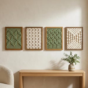 Op de afbeelding: Vier rechthoekige wanddecoraties met ingewikkelde macramé-ontwerpen in saliegroen en off-white. Elk stuk is gevat in een eenvoudige houten lijst en toont gevarieerde geknoopte patronen, waaronder geometrische vormen en bladachtige motieven.