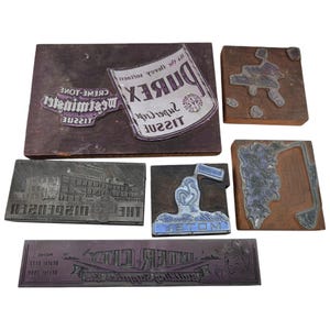 May include: A collection of six vintage metal and wood printing blocks featuring various designs, including text for Durex Super Crepe Tissue, Westminster Creme-Tone Tissue, The Dispenser, Golden Rooster Motel, and Inner City Building Supplies.