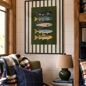 May include: A framed wall art print featuring five stacked fish illustrations in various colors against a dark green background, surrounded by a white and dark green vertical striped border, all enclosed within a thin black frame.
