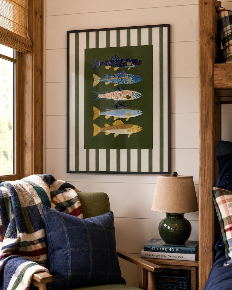 May include: A framed wall art print featuring five stacked fish illustrations in various colors against a dark green background, surrounded by a white and dark green vertical striped border, all enclosed within a thin black frame.