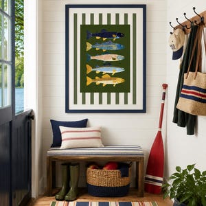 May include: A framed wall art print featuring five stacked fish illustrations in shades of blue, yellow, and orange against a dark green background, surrounded by a white and dark green vertical striped border within a navy blue frame.