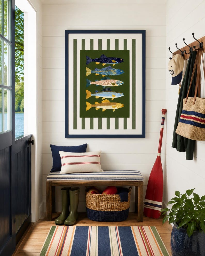 May include: A framed wall art print featuring five stacked fish illustrations in shades of blue, yellow, and orange against a dark green background, surrounded by a white and dark green vertical striped border within a navy blue frame.