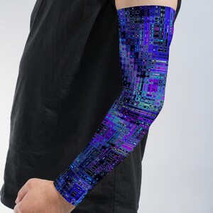 May include: An arm sleeve featuring a vibrant digital pattern of interconnected geometric shapes and flowing lines in shades of deep blue, bright purple, cyan, and black. The fabric is form-fitting and covers the forearm and upper arm area.