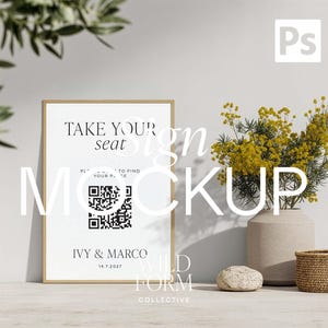 Op de afbeelding: Een verticaal rechthoekig bord in een lichthouten lijst met de zwarte tekst TAKE YOUR SEAT, een QR-code, de namen IVY & MARCO en de datum 14.7.2027. Het bord staat naast een beige vaas met gele bloemen en een klein gevlochten mandje.
