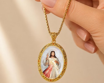May include: A gold-toned oval pendant necklace featuring a central image of Jesus Christ with a red and white light emanating from the chest. The pendant has an intricate filigree border accented with small clear and orange stones on a chain.