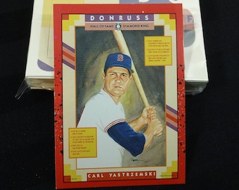 May include: A red, white, and blue baseball card featuring a portrait of Carl Yastrzemski, a Hall of Fame baseball player. The card is from the Donruss Diamond King series.