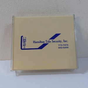 Vintage flip-top papierdispenser met reclame voor Hamilton Title Security, Inc.