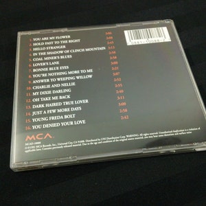 May include: A compact disc case with a black background and a list of song titles. The titles include "You Are My Flower" and "Bonnie Blue Eyes." The case has a clear plastic cover.
