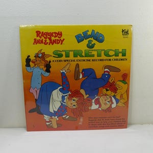 May include: A vintage record album cover featuring Raggedy Ann and Andy, with the title "Bend & Stretch: A Very Special Exercise Record for Children". The cover art shows Raggedy Ann and Andy doing exercise poses with a dog.
