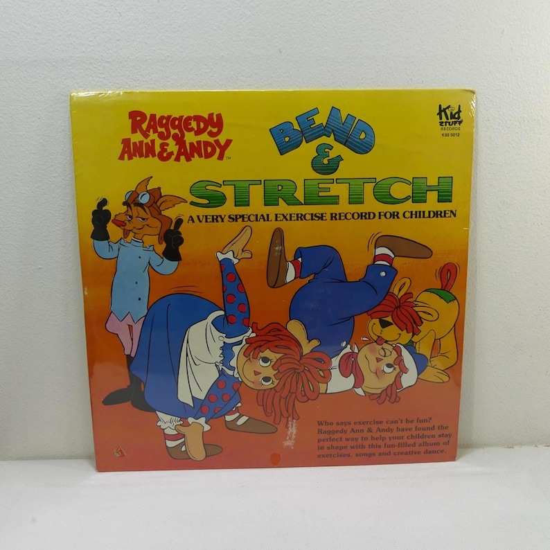 May include: A vintage record album cover featuring Raggedy Ann and Andy, with the title "Bend & Stretch: A Very Special Exercise Record for Children". The cover art shows Raggedy Ann and Andy doing exercise poses with a dog.