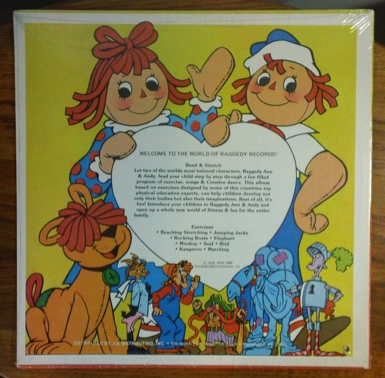 May include: A vintage record album cover featuring Raggedy Ann and Andy, two iconic rag dolls, with a heart-shaped background. The cover is yellow with red polka dots and features a variety of other characters, including a dog, a cat, and a bird. The text on the cover reads "Welcome to the World of Raggedy Records!" and includes a list of exercises for children.