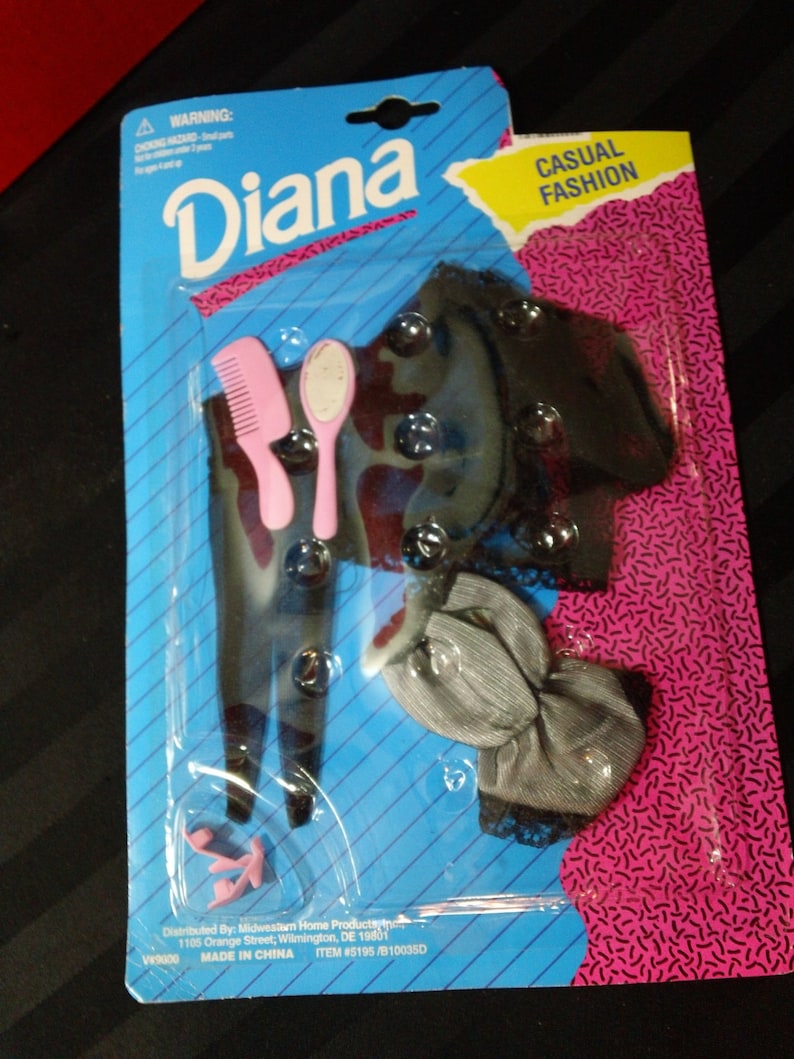May include: A plastic package containing a doll outfit with a black and white top, a gray skirt, a pink comb, a pink hairbrush, and a pair of pink shoes. The package is labeled "Diana Casual Fashion".