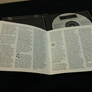 May include: A CD case with a compact disc inside and an open booklet. The disc has text that reads "The Carter Family". The booklet has text and a musical note graphic. The case is on a dark surface.