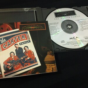 May include: A CD case with the album "The Carter Family" by The Country Music Hall of Fame. The CD is in a clear plastic case, with the album cover visible. The album cover features a photo of the Carter Family.