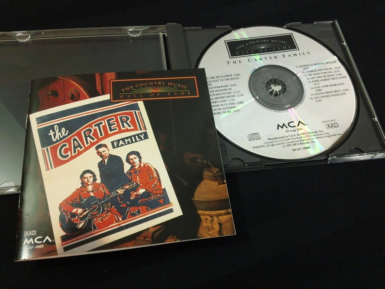 May include: A CD case with the album "The Carter Family" by The Country Music Hall of Fame. The CD is in a clear plastic case, with the album cover visible. The album cover features a photo of the Carter Family.