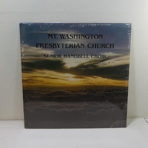 Puede incluir: Una portada de álbum sellada con el texto "MT. WASHINGTON PRESBYTERIAN CHURCH SENIOR HANDBELL CHOIR". La portada muestra una puesta de sol sobre nubes, con tonos naranja, amarillo y azul.
