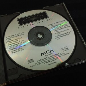 May include: A compact disc from The Carter Family, featuring the album "The Country Music Hall of Fame." The silver disc is in a black jewel case. The disc has song titles like "Bonnie Blue Eyes" and "My Dixie Darling."