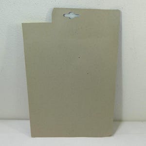 May include: A plain brown cardboard backing card with a hole punched in the top for hanging.