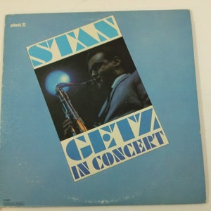 Może przedstawiać: Okładka płyty winylowej w kolorze niebieskim i białym z tekstem "Stan Getz In Concert" i zdjęciem Stana Getza grającego na saksofonie.