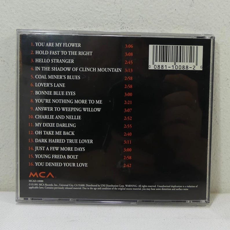 May include: A compact disc case with a black background and white text listing song titles and durations. The CD includes tracks like "You Are My Flower" and "Coal Miner's Blues". The MCA Records logo is visible.