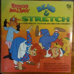 May include: A yellow record cover with Raggedy Ann and Andy on the front. The cover features a red-haired Raggedy Ann, a blue-clad Raggedy Andy, and a yellow dog. The title of the record is "Bend & Stretch: A Very Special Exercise Record for Children".