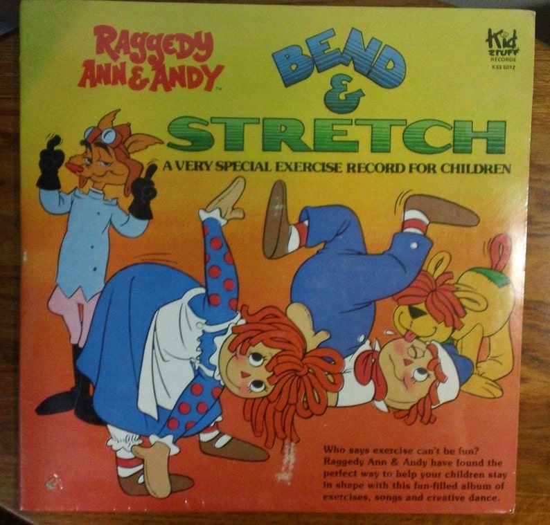 May include: A yellow record cover with Raggedy Ann and Andy on the front. The cover features a red-haired Raggedy Ann, a blue-clad Raggedy Andy, and a yellow dog. The title of the record is "Bend & Stretch: A Very Special Exercise Record for Children".