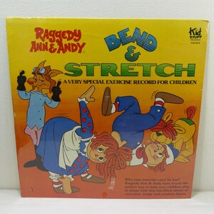 May include: A vintage record album cover featuring Raggedy Ann and Andy, with the title "Bend & Stretch: A Very Special Exercise Record for Children". The cover art shows Raggedy Ann and Andy doing exercise poses, with a dog character in the background.