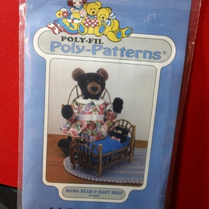 May include: A blue Poly-Fil Poly-Patterns package featuring a Mama Bear and Baby Bert design. The image shows a black bear wearing a floral dress and a baby bear in a wooden bed. The package also features illustrations of teddy bears.