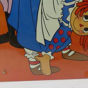 May include: A vintage illustration of a Raggedy Ann doll wearing a blue and white dress with red polka dots. She is standing on her hands with her legs in the air. The doll has red hair and a smiling face.