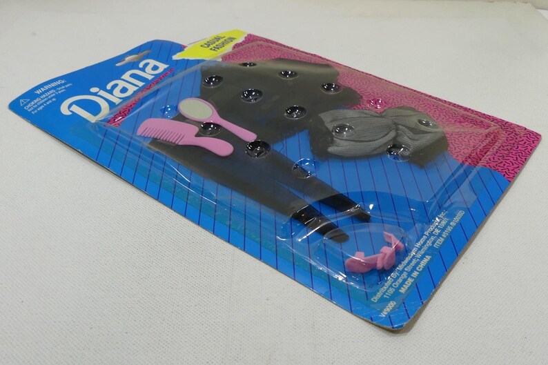 May include: A plastic package containing a black and white doll outfit, a pink comb, a pink hair clip, and a silver hand mirror. The package is labeled "Diana" and "Classic Fashion".