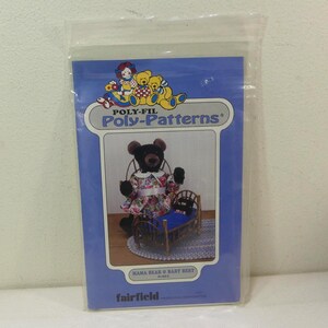May include: A blue Poly-Fil Poly-Patterns package featuring a teddy bear wearing a floral dress and a small bed. The package has the text "MAMA BEAR & BABY BERT" and "fairfield" printed on it. The package is sealed in a clear plastic bag.